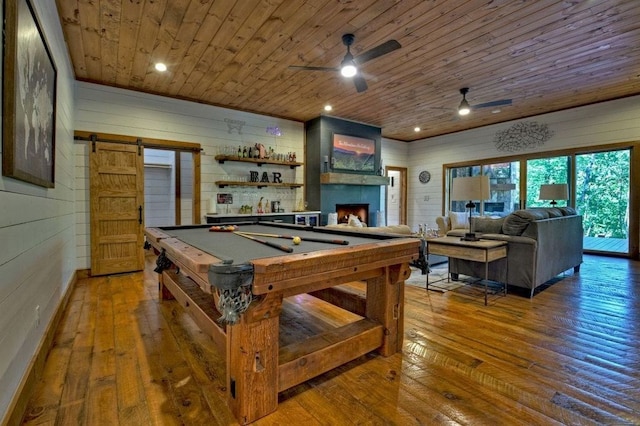 playroom featuring wood ceiling, hardwood / wood-style flooring, wooden walls, pool table, and a barn door