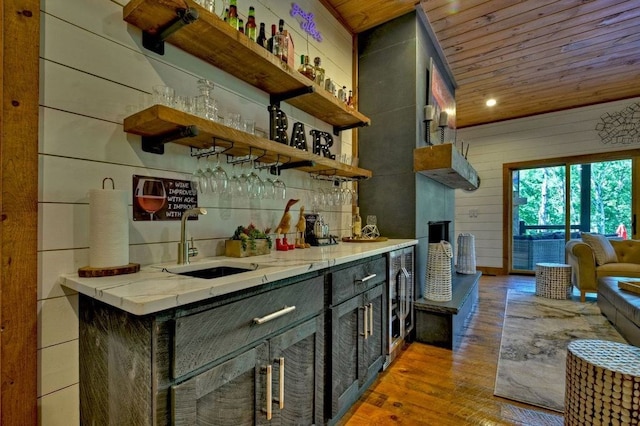 bar with sink, wooden ceiling, wooden walls, and light hardwood / wood-style flooring