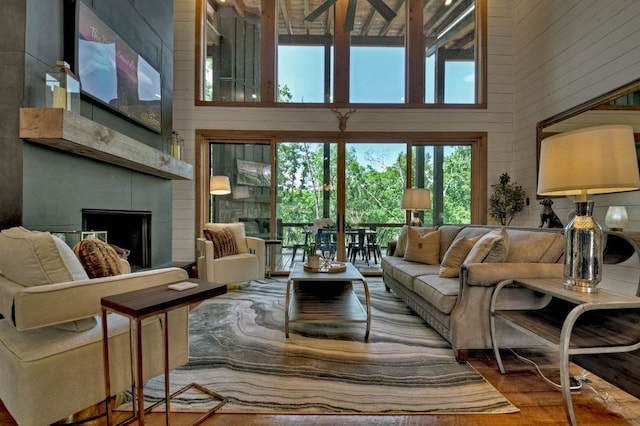 living room with a high ceiling, wooden walls, and a fireplace