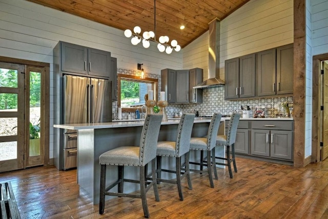 kitchen featuring a kitchen island, pendant lighting, a breakfast bar area, wooden ceiling, and wall chimney exhaust hood