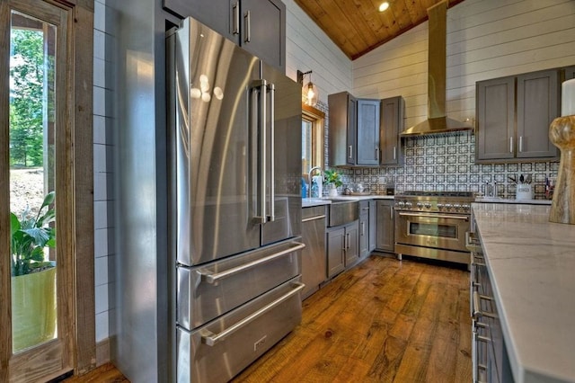 kitchen featuring dark hardwood / wood-style floors, lofted ceiling, premium appliances, wood ceiling, and wall chimney exhaust hood