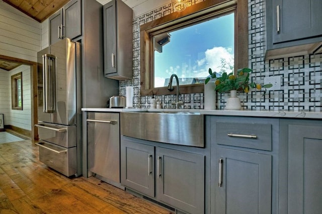 kitchen with gray cabinetry, sink, lofted ceiling, and appliances with stainless steel finishes