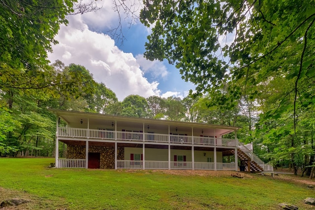 rear view of property featuring a deck, a lawn, and stairway