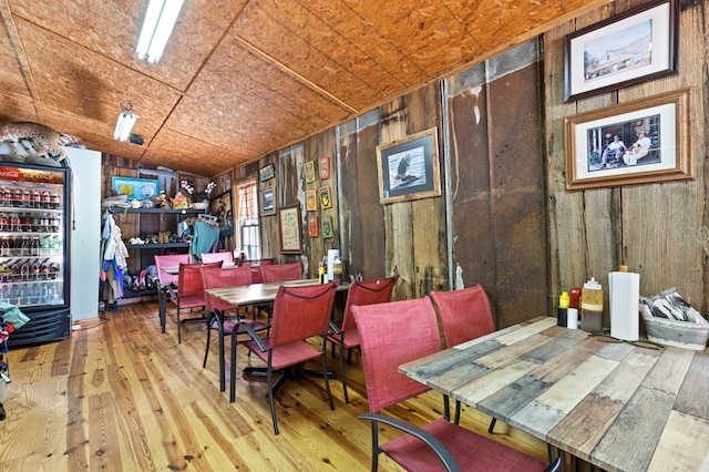 dining space with wooden ceiling, light hardwood / wood-style floors, and wood walls