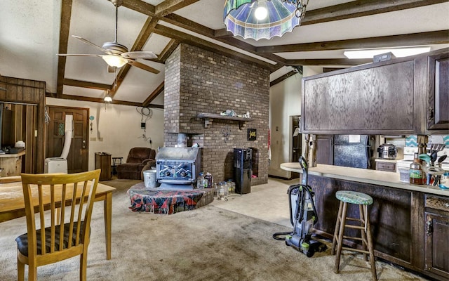 living room featuring a wood stove, ceiling fan, light carpet, and vaulted ceiling with beams