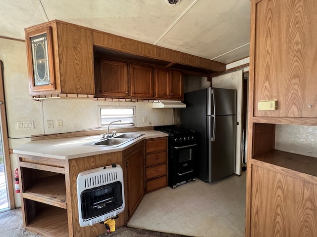 kitchen featuring heating unit, freestanding refrigerator, a sink, black gas range, and under cabinet range hood