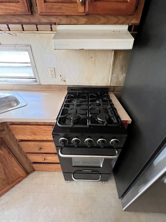 interior details with light countertops, ventilation hood, black range with gas cooktop, and tile patterned floors