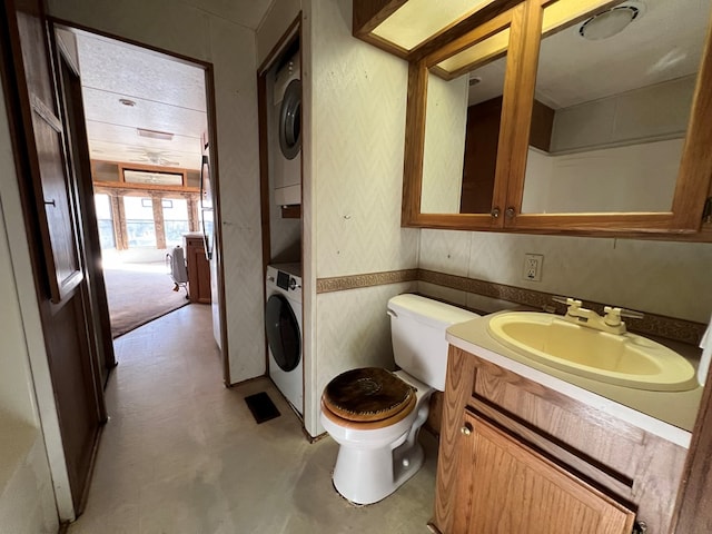 bathroom with vanity, stacked washer and dryer, and toilet