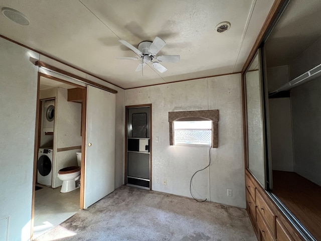 unfurnished bedroom featuring ensuite bath, visible vents, and stacked washing maching and dryer