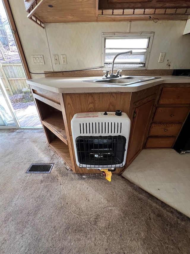 details with visible vents, brown cabinetry, carpet floors, heating unit, and a sink