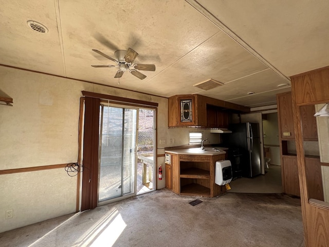 kitchen with a sink, ceiling fan, brown cabinets, freestanding refrigerator, and open shelves