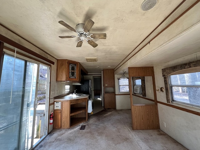 kitchen featuring a wealth of natural light, a ceiling fan, and brown cabinetry