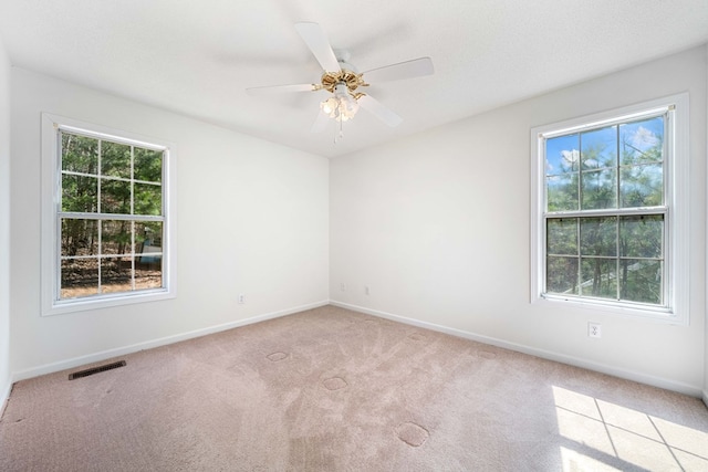 unfurnished room with a wealth of natural light, baseboards, visible vents, and carpet flooring