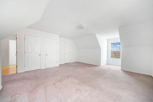 bonus room featuring light carpet, vaulted ceiling, a textured ceiling, and baseboards