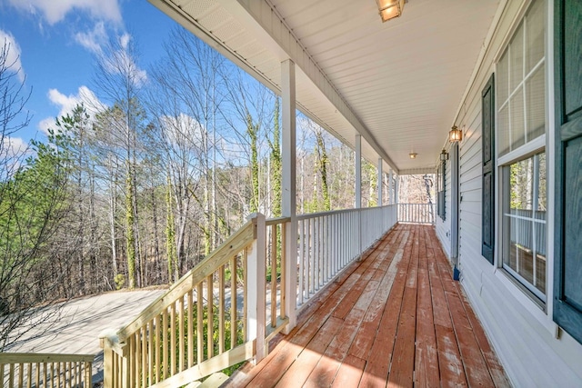 deck featuring covered porch and a wooded view