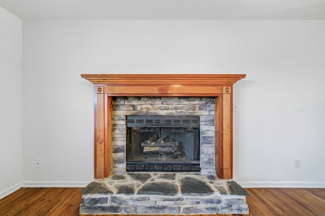 details with a stone fireplace, wood finished floors, and baseboards