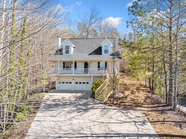 view of front of house featuring a chimney, a porch, concrete driveway, an attached garage, and stairs