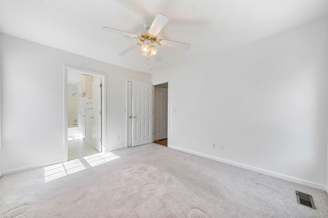 unfurnished bedroom with baseboards, visible vents, carpet flooring, and ensuite bathroom