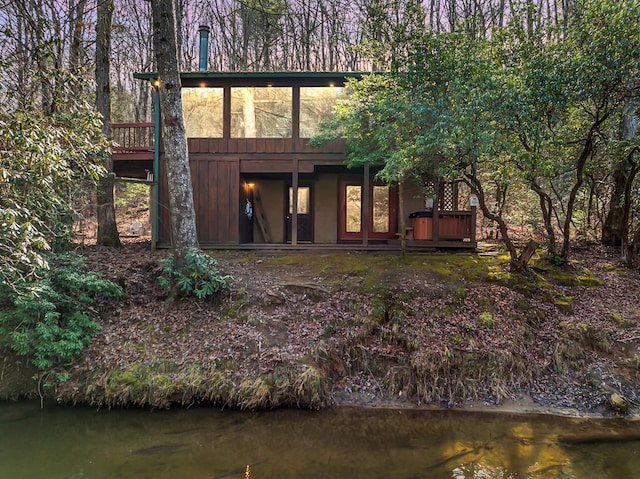 back of property with a water view and a sunroom