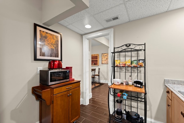 hallway featuring dark tile patterned flooring and a paneled ceiling