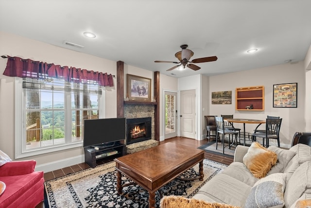 living room with hardwood / wood-style flooring, ceiling fan, and a stone fireplace