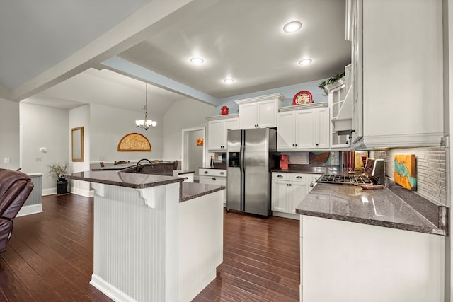 kitchen featuring dark stone countertops, backsplash, stainless steel refrigerator with ice dispenser, white cabinets, and hanging light fixtures