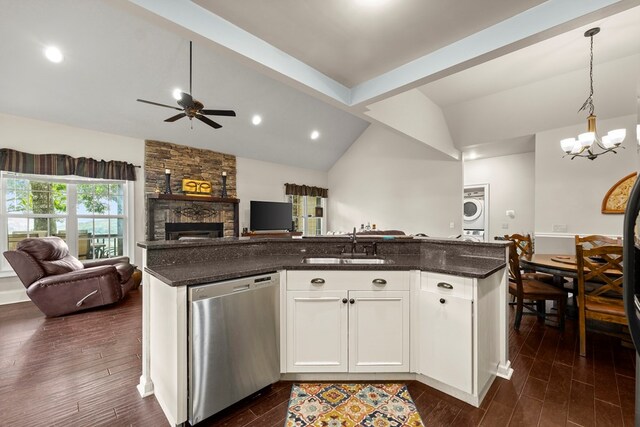 kitchen featuring vaulted ceiling with beams, stainless steel dishwasher, a stone fireplace, ceiling fan with notable chandelier, and stacked washing maching and dryer