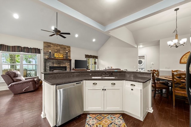 kitchen featuring stacked washer / drying machine, lofted ceiling, hanging light fixtures, stainless steel dishwasher, and white cabinets