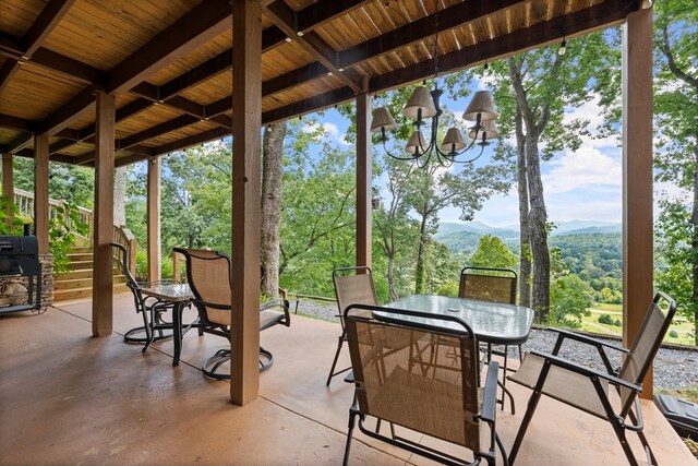 sunroom / solarium with a mountain view, wooden ceiling, an inviting chandelier, and beam ceiling