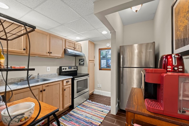 kitchen with light brown cabinets, a paneled ceiling, appliances with stainless steel finishes, sink, and dark tile patterned floors