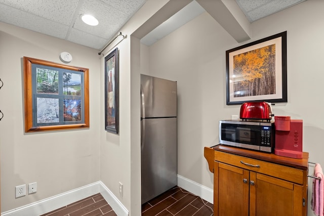 kitchen featuring appliances with stainless steel finishes, dark tile patterned floors, and a paneled ceiling