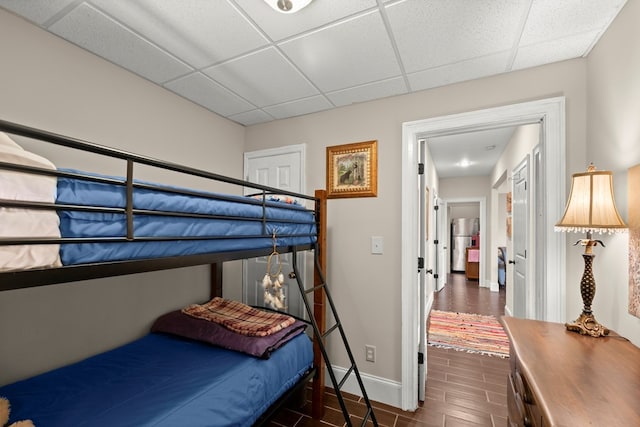 bedroom featuring stainless steel refrigerator, dark hardwood / wood-style flooring, and a paneled ceiling