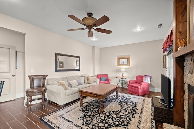 living room with ceiling fan and a stone fireplace