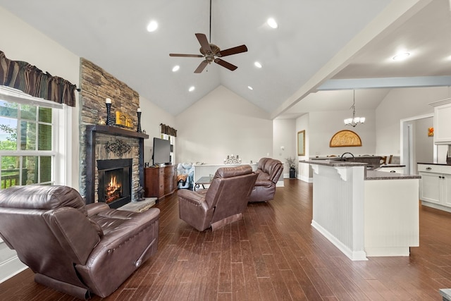 living room with dark hardwood / wood-style flooring, high vaulted ceiling, ceiling fan with notable chandelier, and a stone fireplace