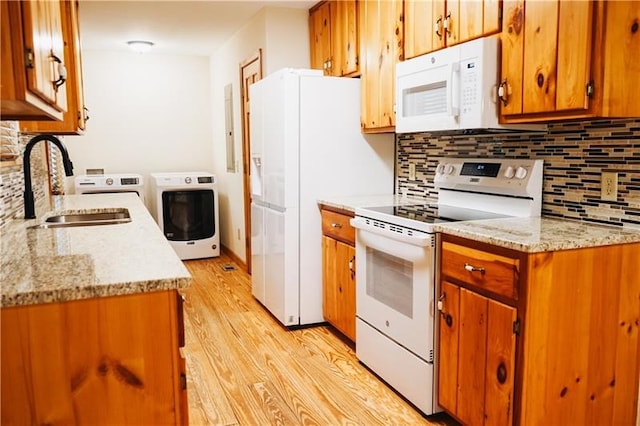 kitchen with decorative backsplash, white appliances, light wood-style floors, brown cabinets, and a sink