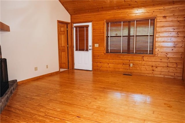 unfurnished living room featuring wood ceiling, vaulted ceiling, light wood-type flooring, wood walls, and baseboards