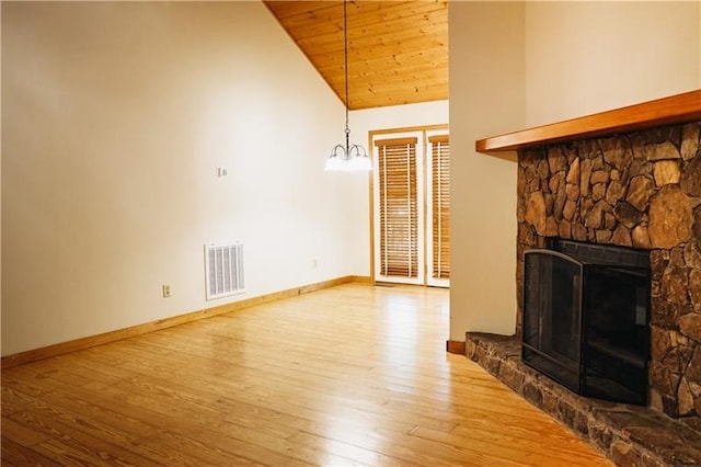unfurnished living room with a stone fireplace, visible vents, hardwood / wood-style flooring, high vaulted ceiling, and baseboards