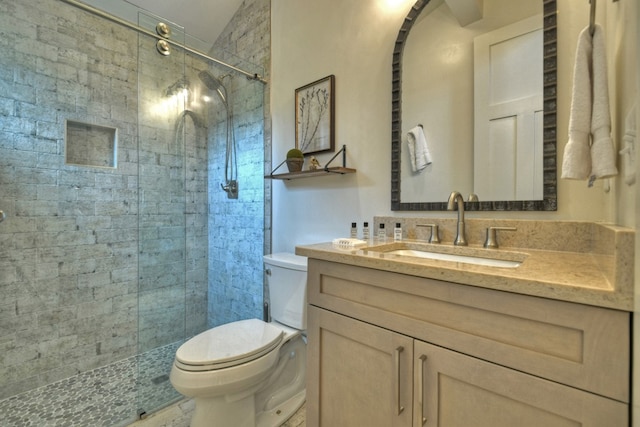 bathroom with vanity, toilet, tiled shower, and vaulted ceiling