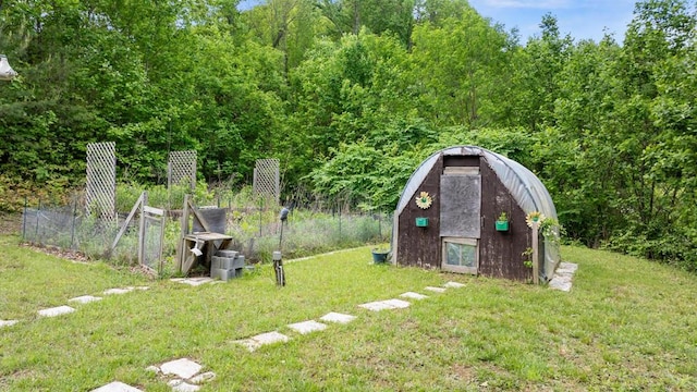 view of grassy yard featuring an outbuilding, a storage unit, and a view of trees