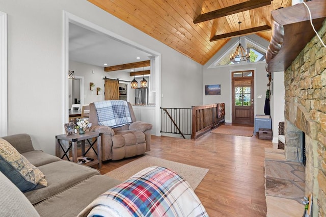 living room featuring wood ceiling, a chandelier, wood finished floors, a barn door, and beamed ceiling