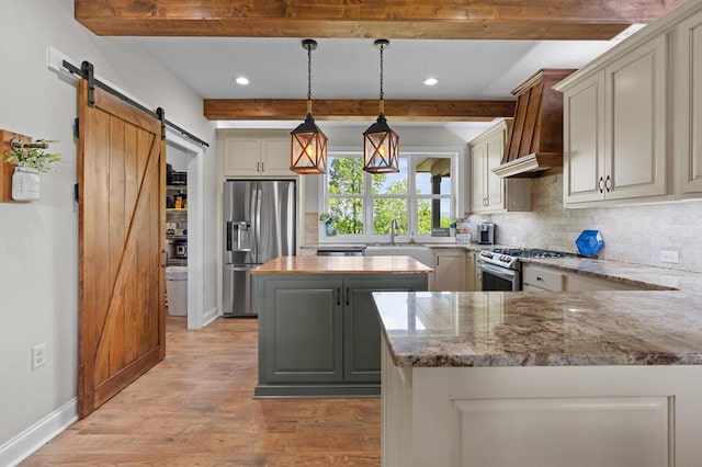 kitchen featuring stainless steel appliances, a barn door, backsplash, light wood finished floors, and beamed ceiling