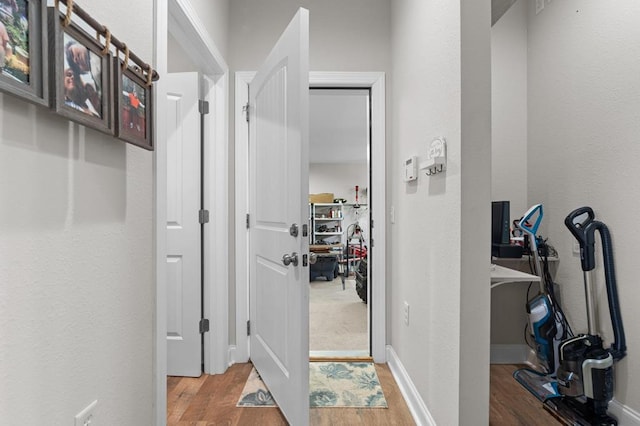 corridor with light wood-type flooring and a textured wall