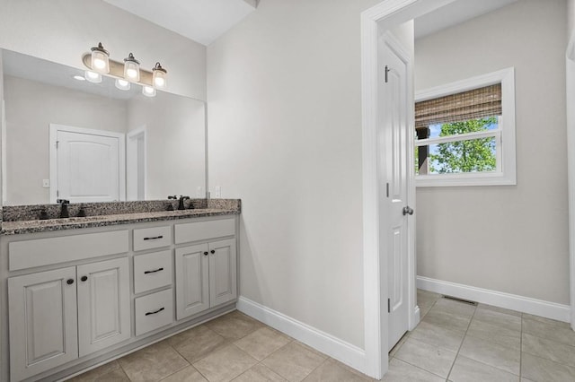 bathroom with baseboards, tile patterned floors, and double vanity