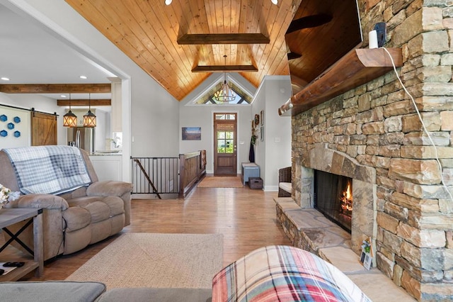 living room with wooden ceiling, light wood finished floors, a stone fireplace, and a barn door
