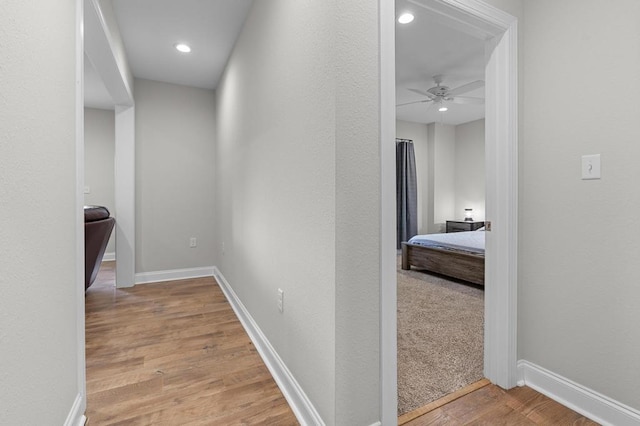 corridor with wood finished floors, baseboards, and recessed lighting