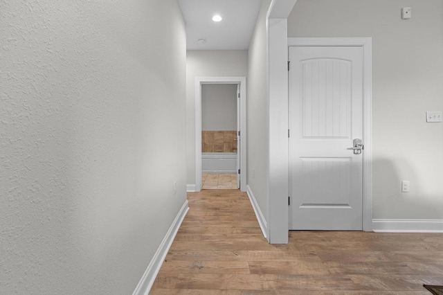 hallway with baseboards, wood finished floors, and recessed lighting
