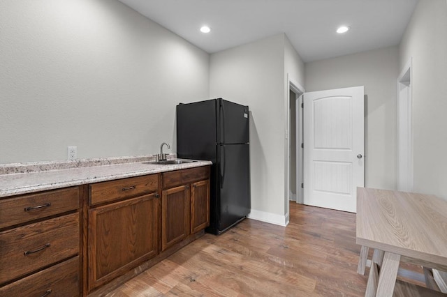 kitchen with freestanding refrigerator, a sink, light wood finished floors, light countertops, and baseboards