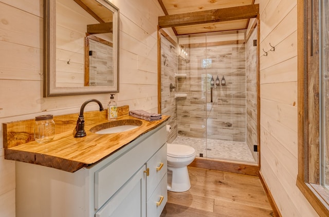 full bathroom featuring wooden walls, wood finished floors, toilet, vanity, and a stall shower