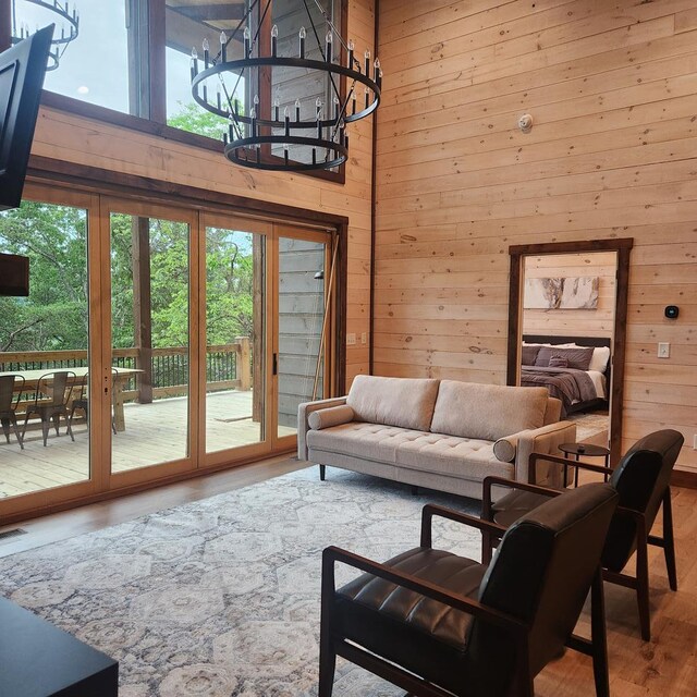 living room featuring wood finished floors, wooden walls, a towering ceiling, and a wealth of natural light