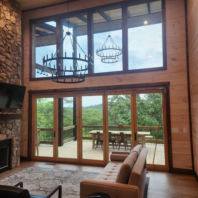 living room with a chandelier, wooden walls, wood finished floors, and a fireplace